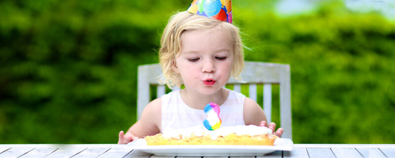 Wir feiern den dritten Geburtstag - Dreijähriges Kind vor einer Geburtstagstorte