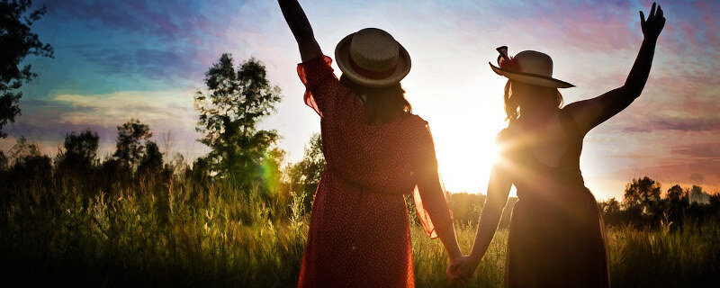 Der Weg zu mehr Mut und Selbstbewusstsein - Zwei Frauen Hand in Hand im Gegenlicht der Abendsonne