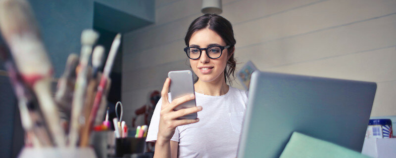 Ständige Erreichbarkeit kostet Konzentration und Arbeitszeit - Junge Frau mit Laptop und Telefon