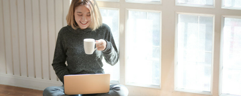Online-Meeting-Teilnehmerin vo dem Laptap mit Tasse in der Hand