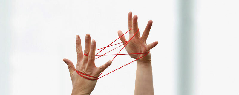 Foto - Händen beim Spiel mit einem roten Faden