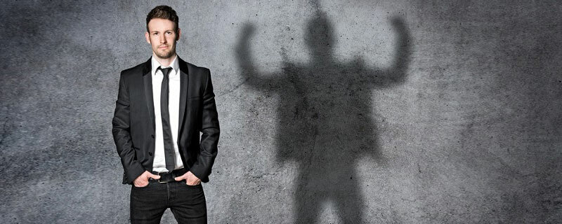 Innere Haltung und Macht - Gelassener Mann mit kraftstrotzendem Schatten an der Wand